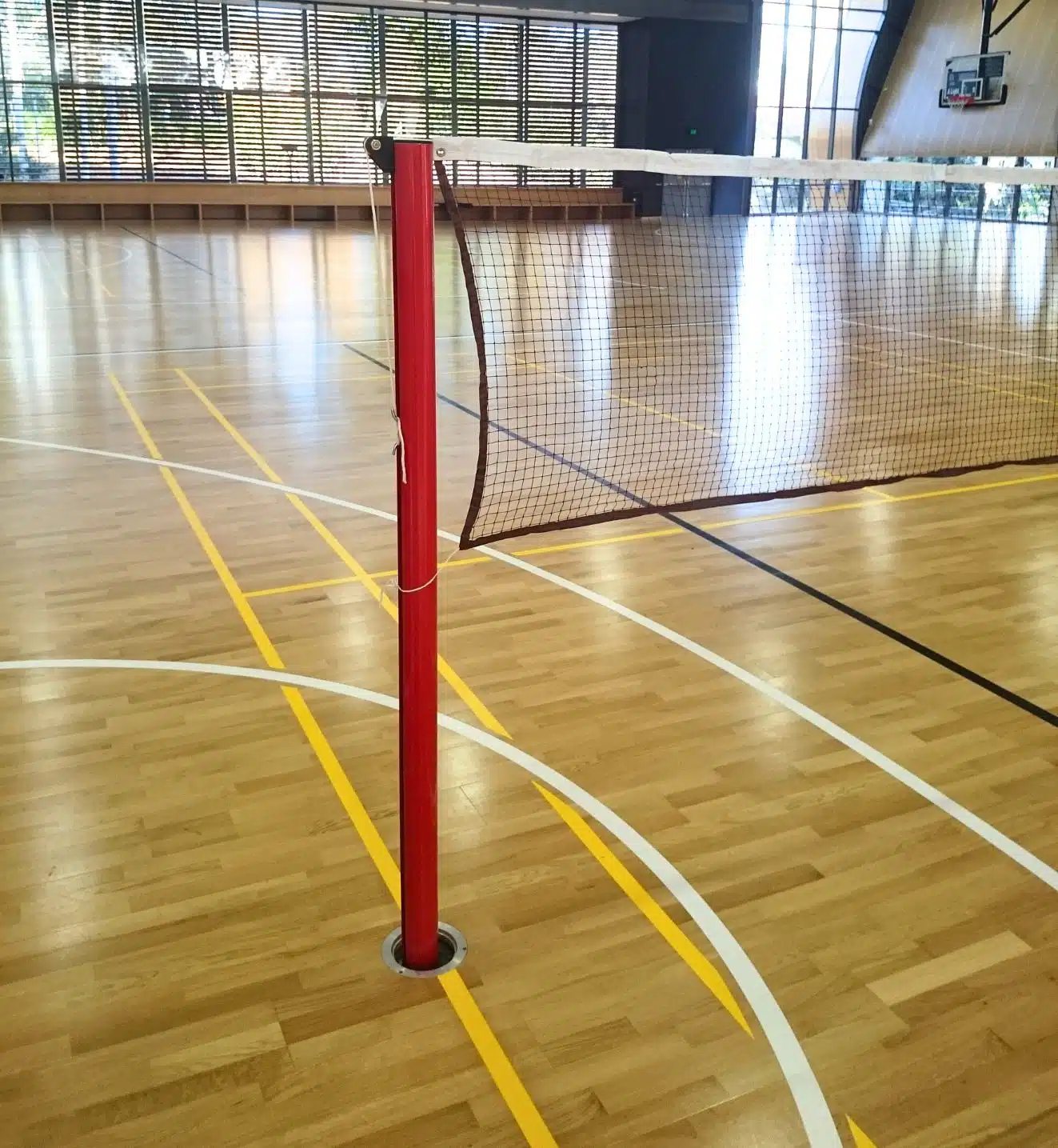 Close-up of Aluline sleeved badminton post installed in timber indoor court