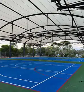 Full Multi-Sport Court Installation – Covered Outdoor Facility by RMA Sport - RMA Sport Full view of a covered outdoor sports court with blue synthetic surface and steel tensile roof