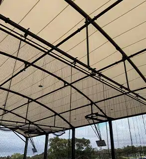 Central Dividing Net & Hoop System – Covered Outdoor Sports Court by RMA Sport - RMA Sport Central view of retractable dividing net and basketball hoop under tensile canopy roof