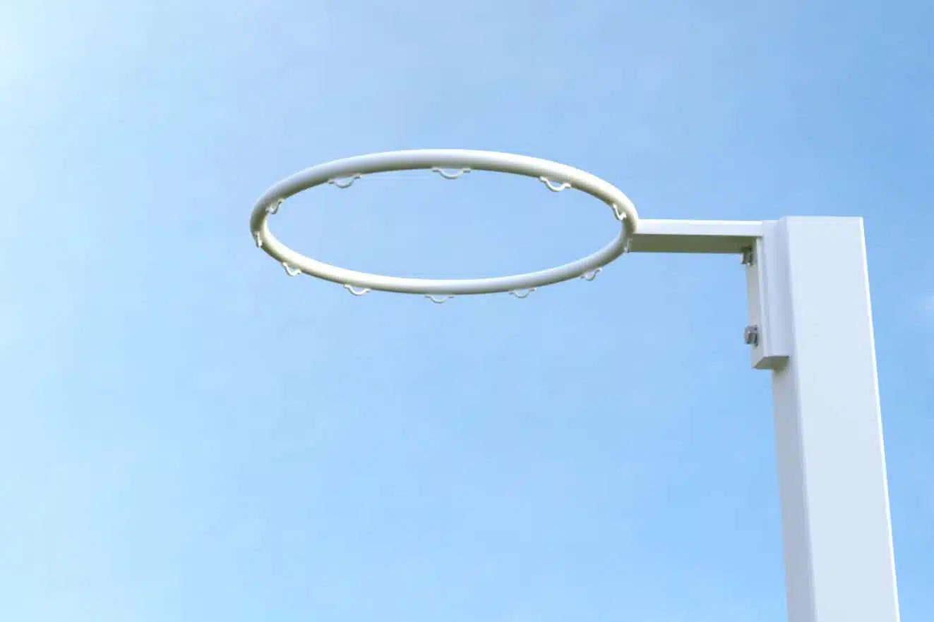 NBES-R3 - RMA Sport White basketball hoop rim attached to a white post against a clear blue sky, no net visible.